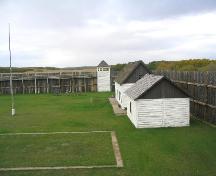 View west at reconstructed buildings, palisade, bastion and a concrete-capped foundation, 2004.; Government of Saskatchewan, Marvin Thomas, 2004.