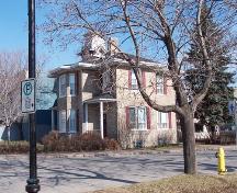 Prise de biais, cette photo laisse entrevoir une partie de la galerie avant et de la façade sud de la maison Albert.; Town of Edmunston