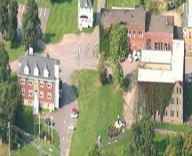 Aerial view of a portion of Butte à Pétard: Municipal Building to the left (south side); former Littles Sisters Convent, site of the first collège built in Memramcook.; Memramcook Valley Historical Society