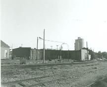 Coner view of the Esquimalt and Nanaimo Railway Roundhouse, showing the 10-stall roundhouse building with attached machine shop and the turntable, 1991.; Parks Canada Agency/ Agence Parcs Canada, Mills Photo No. 2, 1991.