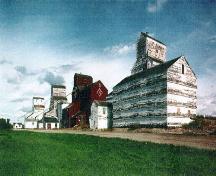 General view of the Inglis elevators, ca. 1996.; Heritage Recording and Technical Data Services, Heritage Conservation Program, RPS, ''Designated Building Heritage Recording Report: Preliminary Record of 5 Grain Elevators, Inglis, Manitoba'', September/October 1996.
