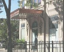 A brass and glass canopy shelters the arched stone entrance, flanked by symbols of the caduceus.; City of Windsor, Planning Department