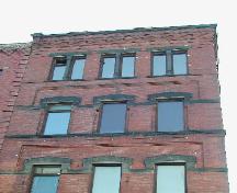 Sur cette photo, nous pouvons voir les étages supérieurs et les fenêtres, le travail de maçonnerie en retrait, les appuis en grès, la corniche, les bandeaux en saillie et les assises en grès. ; City of Saint John 2004