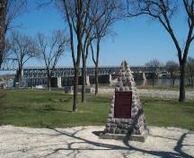 En arrière-plan, le lieu historique national du Canada du Pont-Barrage-à-Rideaux-Caméré-St. Andrews, 2004.; Parks Canada Agency / Agence Parcs Canada, 2004.