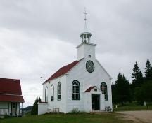 Illustrates the building's façade featuring a bull’s-eye window above the main entrance and the bell tower with cross.; PNB 2004