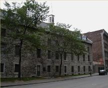 Façade of the Grey Nuns' Hospital, showing the three-and-a-half storey volume under a prominent, gable ended roof, and rough masonry construction, 2004.; Parks Canada Agency / Agence Parcs Canada, 2004.