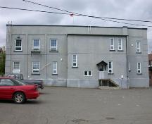 This image displays the exterior finish in stucco and the flat roof with a slight serrated cornice.; PNB 2004