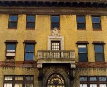Central entry is accented with an elaborate, arched, cut stone surround and cantilevered balcony on the three-storey Italianate Romanesque - Renaissance Revival style building.; City of Windsor Collection
