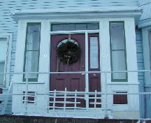 This image shows the enclosed central entrance with a low pitched roof, four-paned transom window and two-paned sidelights, 2006; City of Saint John