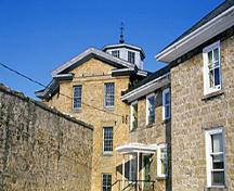 Detail view of the Huron County Gaol, showing the three-storey octagonal central block under a shallow octagonal roof surmounted by a lantern, 1995.; Parks Canada Agency / Agence Parcs Canada, J. Butterill, 1995.