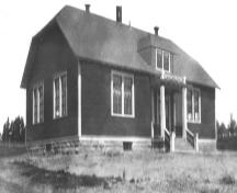 Historic photo of the school, taken from the southeast, showing the double windows for each classroom and the attic.; Memramcook Valley Historical Society