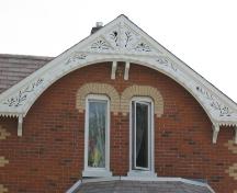 Featured is the facade gable with decorative bargeboard and paired elliptical windows.; Beatrice Tam, 2008.