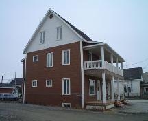 This photograph presents the building at the corner of Canada and Bois Hébert streets with its steep gable roof. ; Village of Saint-Quenting