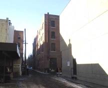 This  image illustrates the rear east-facing and south-facing facades of the Armstrong Block looking from the southeast. Note the historic painted sign at the top of the east wall. (2004); City of Edmonton, 2004