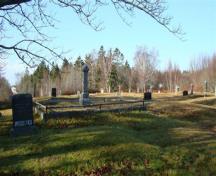 L'annexe de l'ancien cimetière des pionniers présente des parcelles terrassées avec de beaux arbre agés qui ombragent le cimetière; Grand Manan Historical Society