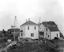 Cette image historique montre la maison du gardien du phare Swallowtail, construite en 1958, avec ses dépendances et l'abri à bateaux.; Laurie Murison