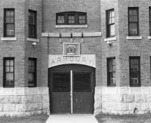 View of the Armoury showing the projecting twin-towered frontispiece of the main facade with troop door, 1987.; Department of National Defence / ministère de la Défense nationale, 1987.