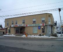 This image presents the concrete block structure clad in bricks at the corner of Canada and Mgr. Martin streets.; Village of Saint Quentin