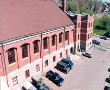 Rear view of the Armoury, showing the smooth, load bearing exterior walls with deeply recessed windows, 1994.; Parks Canada Agency / Agence Parcs Canada, 1994.