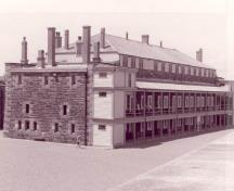 Vue générale de l'édifice Cavalier, montrant son volume rectangulaire à trois étages coiffé d’un toit à pan coupé avec une véranda à colonnes de deux étages sur sa longue façade qui se termine à chaque extrémité par une tour d'escalier, 1995.; Agence Parcs Canada / Parks Canada Agency, Rhona Goodspeed, 1995.