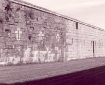 Vue générale de la Galerie de la contrescarpe, montrant les meurtrières de fusillade verticales bordées de granit taillé, les meurtrières verticales de fusillade avec linteau plat en un seul bloc et les pierres d’angle en granit taillé, 1995.; Agence Parcs Canada / Parks Canada Agency, Rhona Goodspeed, 1995.