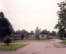 Front elevation of Building P-148 (School), showing the main façade of the building and the front driveway, 1992.; Department of National Defence / Ministère de la Défense nationale, 1992.