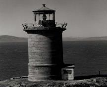 Vue générale du phare, qui montre le garde-fou avec des poteaux en fer forgé et des rampes de cordage à quatre rangées qui entoure la plate-forme de la lanterne, vers 1970.; Transport Canada / Transports Canada, circa / vers 1970.