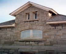 Vue de la façade latérale du bâtiment d’entretien, qui montre les murs en pierre calcaire à bossage rustique, posée en assises irrégulières, 1988.; Parks Canada Agency / Agence Parcs Canada, 1988.