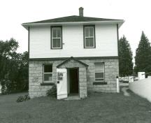 View of the main entrance of the Lower Brewers Defensible Lockmaster's House, showing the symmetrical elevations with regular placement of the windows and doors, 1989.; Department of Public Works / Ministère des Travaux publics, 1989.