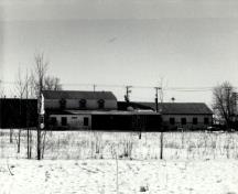 View of the Woodworking Shop, showing the exterior form of the building, which speaks to the transitory nature of many of the activities it accommodated and its workshop function, 1989.; Agence Parcs Canada / Parks Canada Agency, 1989.