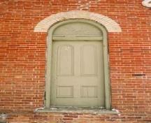 View of the exterior of Former Atha School House, showing the round-headed upper panelling of the door, 2005.; Department of Public Works and Government Services / Ministère des Travaux publics et services gouvernementaux, Alice Da Silva, 2005.
