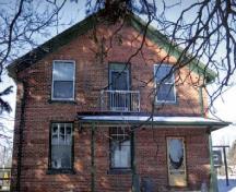 View of the side of the Former Commercial Hotel, showing its two-storey red brick construction, 2005.; Public Works and Government Services Canada / Travaux publics et services gouvernementaux Canada, 2005.