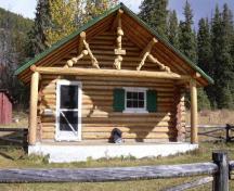View of the main entrance of Brazeau Warden Cabin, showing the one storey rectangular massing with a overhanging, medium-pitched gable roof over the front to form a porch, 2005.; Parks Canada Agency / Agence Parcs Canada, 2005.