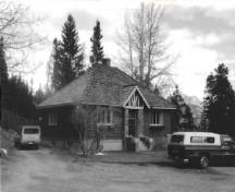 Façade of the Upper Hot Pool Residence, showing its Tudor-Rustic decorative detailing on the front porch gable, and the distinctive treatment of limestone on the porch surrounds.; E. Mills, Parks Canada Agency / Agence Parcs Canada, 1990.