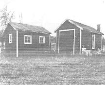 À gauche, vue générale des façades est et nord du Hangar à bois, 1992.; Department of Public Works / Ministère des Travaux publics, (A & E Services -- CPS, WRO), 1992.
