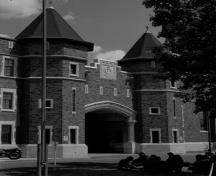 View of main entrance to Salaberry Armoury, showing the red brick and white limestone exterior with the central arched main entrance flanked by round towers, 1989.; Parks Canada Agency / Agence Parcs Canada, Henri Langlois, 1989.