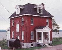 Vue du bâtiment 77, qui montre la volumétrie cubique sur deux étages et demi et le toit en croupe brisé, vers 2004.; Agence Parcs Canada / Parks Canada Agency, circa / vers 2004.