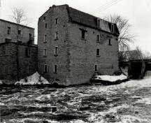 Vue de l’usine ouest, qui montre les murs extérieurs en pierre, 1972.; Agence Parcs Canada / Parks Canada Agency, 1972.