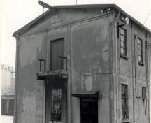 Vue de l'extérieur de l'entrepôt et bureau, qui montre le solide coquille en béton renforcé par une charpente en acier, 1990.; Parks Canada Agency / Agence Parcs Canada, 1990.
