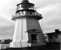 View of the Lighttower, showing its tapered massing consisting of a short, octagonal shaft capped by a heavy concrete gallery balustrade.; Garde côtière canadienne / Canadian Coast Guard