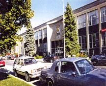 Façade de l’édifice du gouvernement du Canada, qui montre la disposition des fenêtres qui sont groupées en bandes verticales dans de grandes ouvertures rectangulaires superposées séparées par des panneaux d’allège en émail vitrifié, 1997.; Public Works and Government Services Canada / Travaux publics et Services gouvernementaux Canada, 1997.