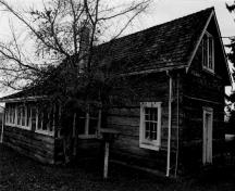 South and east façades of Kinkade Farmstead, showing the squared-log hand hewn walls with dovetailed corner-notches, the gabled end walls of cedar and the cedar shingle pitched roof, 1999.; Parks Canada Agency / Agence Parcs Canada, Mills, 1999.