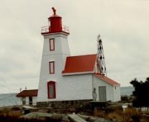 View of the Lighthouse and Dwelling at Gereaux Island, showing the regular spacing and vertical alignment of the tower’s window openings and the door pediment, 1981.; Parks Canada Agency / Agence Parcs Canada, 1981.