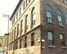 Vue en angle du centre de recrutement, qui montre l’emploi de la pierre rustiquée au rez-de-chaussée, d’une pierre de taille fine au premier étage et de la brique de couleur chamois au second, 1990.; Department of National Defence / Ministère de la Défense nationale, 1990.