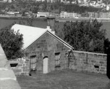 Vue du bâtiment 32, qui montre la façade symétrique percée par une porte flanquée de deux fenêtres, 1991.; Agence Parcs Canada / Parks Canada Agency, 1991.