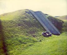Angled view of RMC Building 30b, showing the spare, precise stone walls, symmetrically arranged to protect its single entrance, 1993.; Parks Canada Agency / Agence Parcs Canada, 1993.