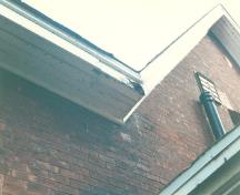 Detail view of the side of RMC Building 36, showing the wooden details of the roof eaves, 1993.; Parks Canada Agency / Agence Parcs Canada, 1993.