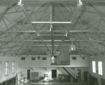 Interior view of the Armoury, showing the wide unobstructed drill hall with Fink roof trusses, 1989.; Department of National Defence / Ministère de la Défense nationale, 1989.