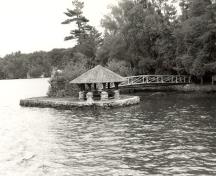 View of the exterior of the Gazebo, showing the picturesque quality as expressed through its small scale, the Rustic style design and use of local materials, 1992.; Parks Canada Agency / Agence Parcs Canada / Historica Resources Ltd., 1992.
