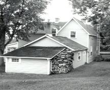 Vue en angle de la résidence du maître-éclusier, qui montre la volumétrie sur deux étages et le parement de planches à clins des murs extérieurs, 1989.; Parks Canada Agency / Agence Parcs Canada, Couture, 1989.